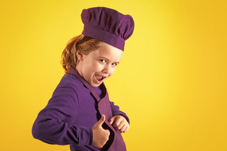 Child chef cook. Child wearing cooker uniform and chef hat preparing food, studio portrait.の写真素材