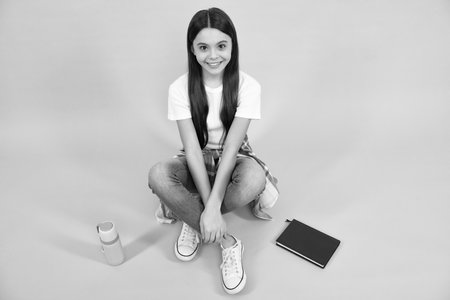 Hipster female teenager in trendy clothes. Child girl with skateboard isolated on studio background. Happy teenager, positive and smiling emotions of teen girl.の写真素材