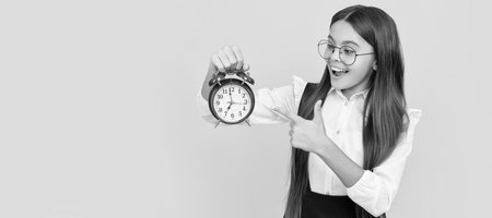 punctual teen girl checking time. happy nerd child pointing finger on alarm clock. Teenager child with clock alarm, horizontal poster. Banner header, copy space.の写真素材