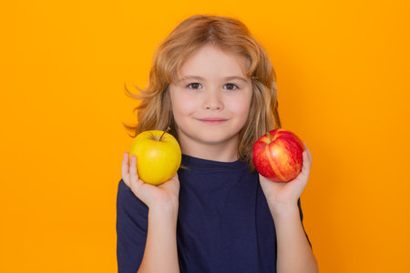 Kid with apple in studio. Studio portrait of cute child hold apple isolated on yellow background.の写真素材