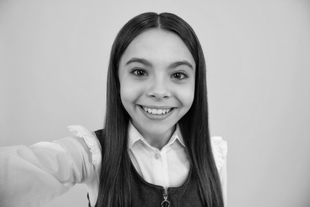 Funny teenager girl making selfie posing on yellow background.の写真素材