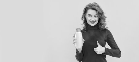 happy woman use shower gel. girl curly hair hold shampoo bottle show thumb up.の写真素材