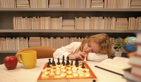 Tired child sleeping near chess in classroom. Chess school and education concept.の写真素材