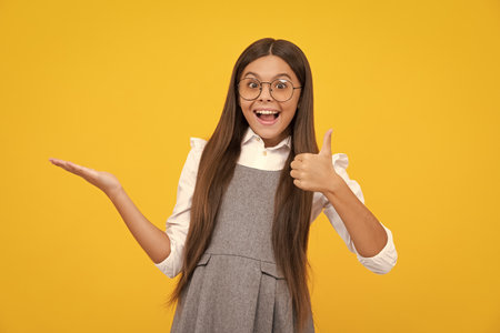 Teenager child pointing to the side with a finger to present a product or idea. Teen girl in casual outfit pointing empty space. Excited face, cheerful emotions of teenager girl.の写真素材
