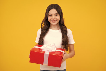 Child with gift present box on isolated background. Presents for birthday, Valentines day, New Year or Christmas. Happy teenager, positive and smiling emotions of teen girl.の写真素材