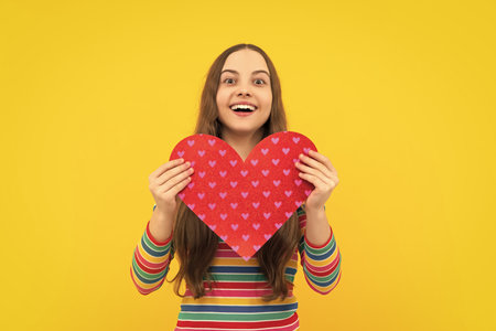 Teenage girl hold shape heart, heart-shape sign. Child holding a red heart love holiday valentine symbol.の写真素材