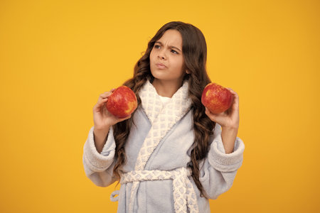 Teenager child with apple on yellow isolated background. apples are good for children. Thinking pensive clever teenager girl.の写真素材