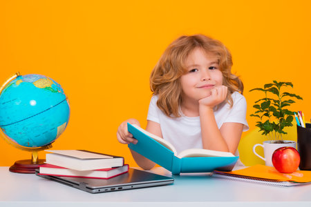 School child reading book. Smart caucasian school boy kid pupil student going back to school. Education kids. School boy isolated on yellow studio background.の写真素材