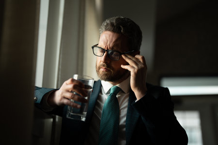 Tired, headache and eye strain from laptop. Businessman with stress, burnout and fatigue eyestrain. Business man rubbing tired eyes after computer work.の写真素材