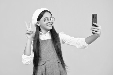 Kids selfie. Mobile online shopping. Cute teen child girl paying with phone, texting and chatting on smartphone. Happy face, positive and smiling emotions of teenager girl.の写真素材