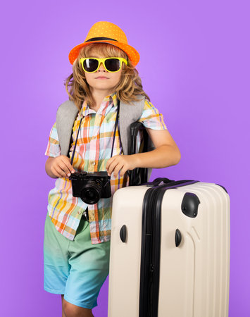 Child traveler with suitcase isolated on studio background. Tourist kid boy. Portrait of child travel with travel bag. Travel, adventure, vacation.の写真素材