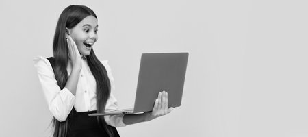 happy kid in school uniform study on laptop, online education. School girl portrait with laptop, horizontal poster. Banner header with copy space.の写真素材