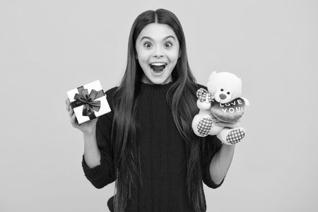 Excited kids face. Teenager child with present box. Teen girl giving birthday gift. Present, greeting and gifting concept. Amazed expression, cheerful and glad.の写真素材