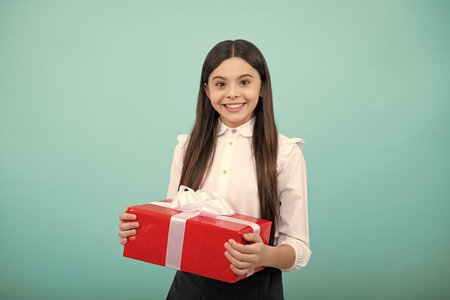 Teenager child with gift box, studio isolated background. Present for birthday, Valentines day, New Year or Christmas. Kid hold present box with gift ribbon bow.の写真素材