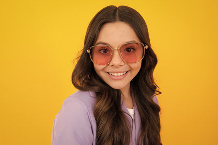 Teenager child with poor eyesight wear sunglasses, looking squinting. Kids glasses. Funny surprised adorable girl in round glasses having astonished shocked facial expression.の写真素材