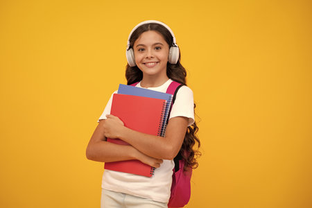 School girl, teenage student in headphones and books on isolated studio background. School kids with backpack.の写真素材