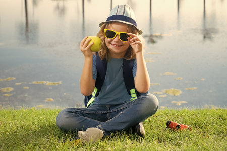 Cute blond kid with binoculars wearing explorer hat and backpack on nature. Child explorer hiking and adventure.の写真素材
