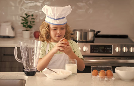 Child chef cook. Funny child stand at kitchen table have fun baking, doing bakery preparing food at home kithen. Healthy food. Little chef preparing healthy meal.の写真素材