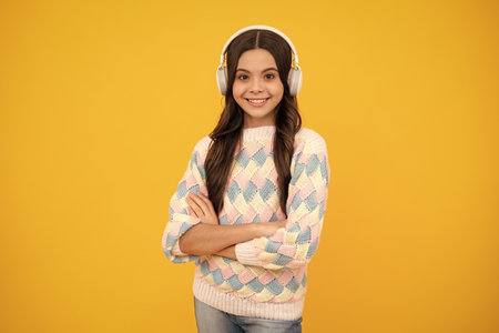 Young teen child listening music with headphones. Girl listening songs via wireless headphones. Wireless headset device accessory.の写真素材