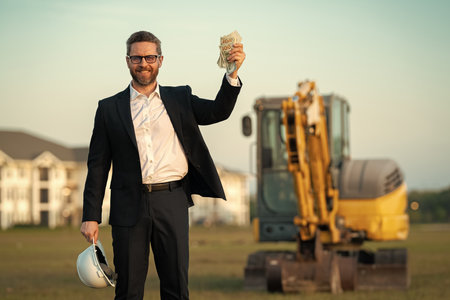 Architect at a construction site. Architect man in helmet and suit at modern home building...