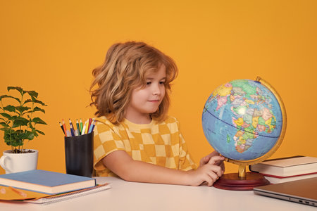 School child student learning in class looking at globe during geography lesson at school. Elementary school child. Portrait of funny pupil learning.の写真素材