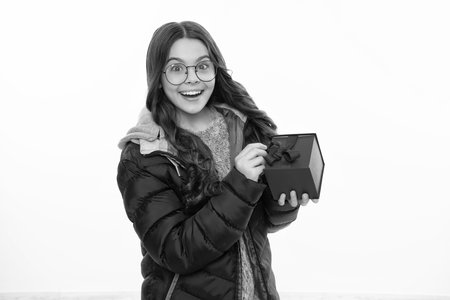 Excited face, cheerful emotions of teenager girl. Teenager child holding gift box on isolated background. Gift for kids birthday. Christmas or New Year present box.の写真素材
