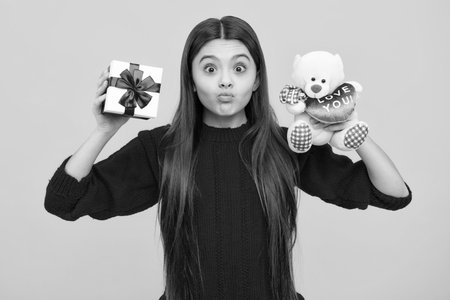 Funny face. Emotional teenager child hold gift on birthday. Funny kid girl holding gift boxes celebrating happy New Year or Christmas.の写真素材