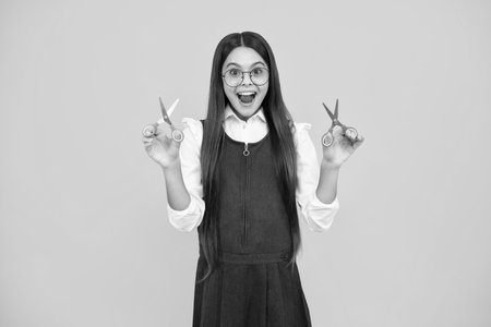 Teenage school girl with scissors, isolated on yellow background. Child creativity, arts and crafts, diy tools.の写真素材