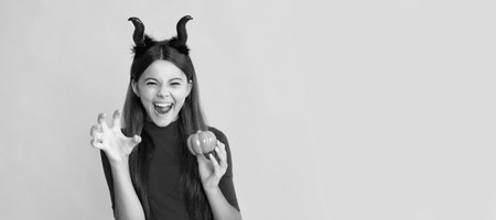 evil child in imp horns. happy halloween. devil kid with pumpkin. trick or treat. Halloween kid girl portrait, horizontal poster. Banner header with copy space.の写真素材