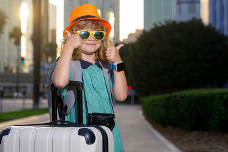 Child with travel suitcase on vacation. Kids travel and adventure concept. Child boy going on vacation holding luggage travel bag outdoor.の写真素材