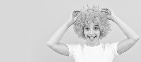 happy egoistic funny girl with fancy look wearing orange hair wig and princess crown, winner. Woman isolated face portrait, banner with copy space.の写真素材