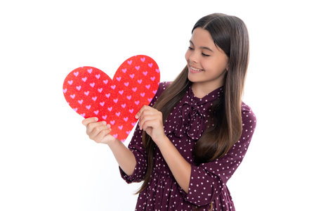 Lovely child girl 12, 13, 14 years old with shape heart love holiday and valentine symbol. Birthday day. Portrait of happy smiling teenage child girl with red heart isolated on white background.の写真素材