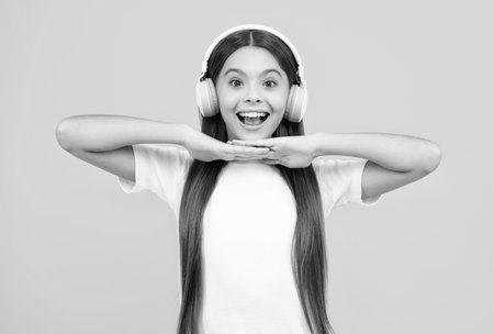 Stylish teenage girl listening to music with headphones. Kids lifestyle concept. Wireless earphones. Excited teenager, glad amazed and overjoyed emotions.の写真素材