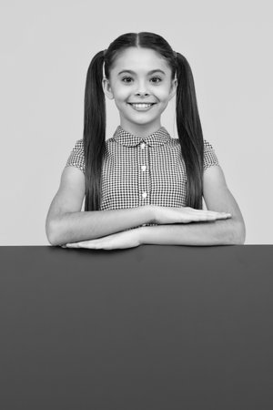 Teenage girl holds a blank for notification informing. Advertisement and sale. Markets and shops sales concept, blank board for copy space. Happy positive and smiling emotions of teen girl.の写真素材