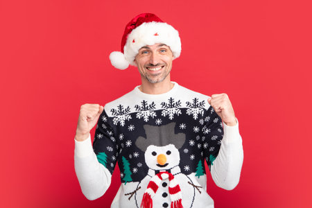Man in holiday sweater and Santa hat on studio background. Christmas sale or special winter offer.の写真素材