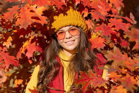 smiling child in sunglasses at autumn leaves on natural backgroundの写真素材