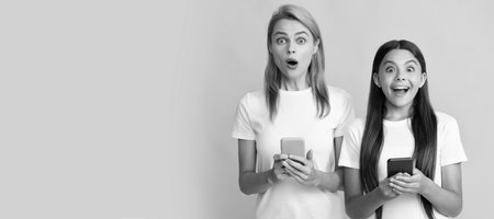 Mother and daughter child banner, copy space, isolated background. showcked woman mom and kid chatting online using modern smartphone, communication.の写真素材