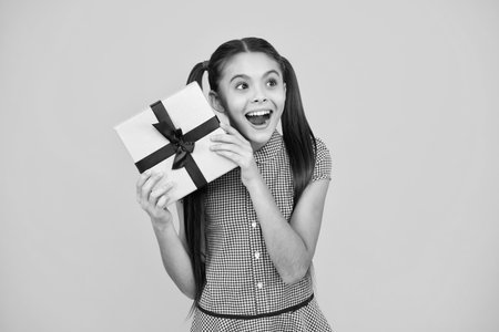 Amazed teenager. Child with gift present box on isolated background. Presents for birthday, Valentines day, New Year or Christmas. Excited teen girl.の写真素材