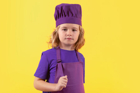 Child chef cook. Child wearing cooker uniform and chef hat preparing food, studio portrait.の写真素材