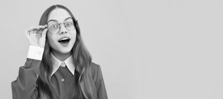 Curious school age girl child look through eyeglasses yellow background, curiosity. Child face, horizontal poster, teenager girl portrait, banner with copy space.の写真素材
