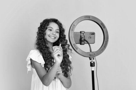 Child vlogger making video blog on phone. Blogging weblog and vlog. Teen girl blogger influencer recording video for social media. Happy teenager, positive and smiling emotions of teen girl.の写真素材