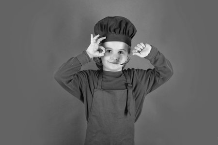 Funny kid chef cook with spoon. Chef child preparing healthy food. Studio portrait of child with chef hats.の写真素材