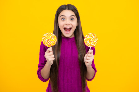 Excited face. Teenage girl with lollipop, child eating sugar lollipops, kids sweets candy shop. Amazed expression, cheerful and glad.の写真素材