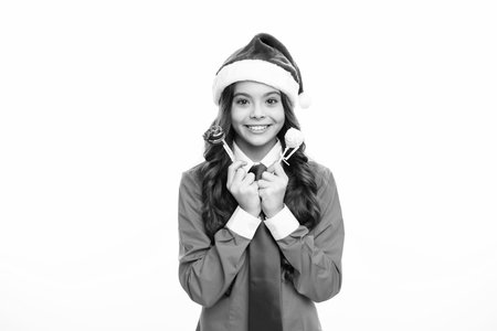 Happy Christmas and New Year. Teenage girl in a Santa hat and blue shirt hold christmas sweets lollipop. Christmas kids holiday. Emotional face expression. Christmas party.の写真素材