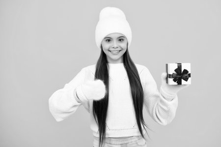 Teenager child hold gift. Funny kid girl in winter hat holding gift boxes celebrating happy New Year or Christmas. Winter holiday.の写真素材