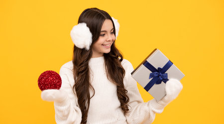 Portrait of teenager child girl 12, 13, 14, years old holding Christmas gift box. Teen giving birthday gift.の写真素材