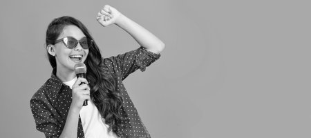 happy teen girl singer blogging online with selfie led and microphone, karaoke online. Horizontal poster of isolated child face, banner header, copy space.の写真素材