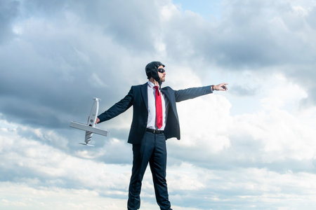 entrepreneur in suit and pilot hat launch plane toy on sky backgroundの写真素材