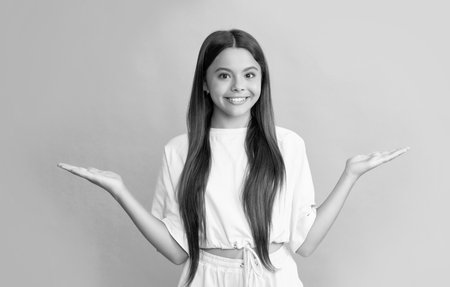 happy teen girl presenting product making choice on blue background with copy space, choiceの写真素材