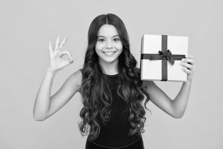Child with gift present box on isolated background. Presents for birthday, Valentines day, New Year or Christmas. Happy girl face, positive and smiling emotions.の写真素材
